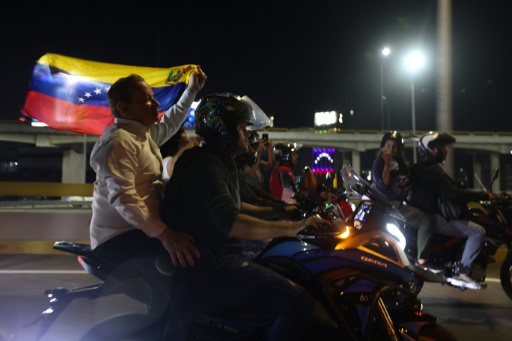 L'opposant Juan Pablo Guanipa, assis à l'arrière d'une moto, tient un drapeau vénézuélien après sa sortie de prison, le 8 février 2026 à Caracas