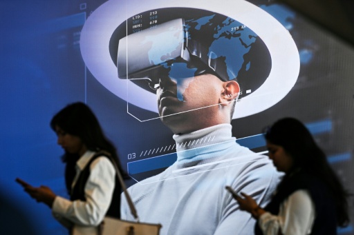 Des visiteuses devant une affiche présentant un casque de réalité virtuelle, lors du Sommet sur l'impact de l'IA à New Delhi, le 17 février 2026, en Inde