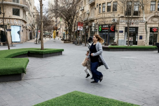 Une femme et son enfant courent se mettre à l'abri après que l'armée israélienne a annoncé avoir détecté des tirs de missiles d'Iran en direction du pays, le 28 février 2026 à Jérusalem