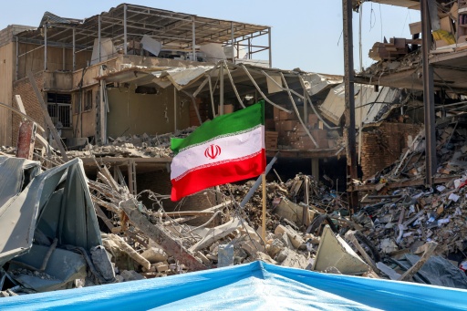 Un drapeau iranien planté dans les décombres d'un immeuble détruit, près de la place Ferdowsi à Téhéran, le 3 mars 2026