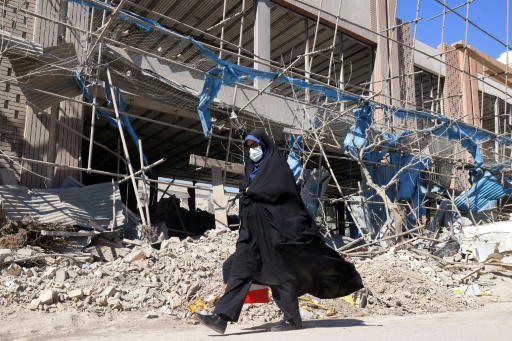 Une femme passe devant des bâtiments fortement endommagés place Ferdowsi à Téhéran, le 3 mars 2026 en Iran