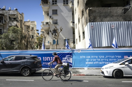 Un cycliste passe devant un immeuble endommagé par un missile iranien, le 8 mars 2026 à Tel-Aviv
