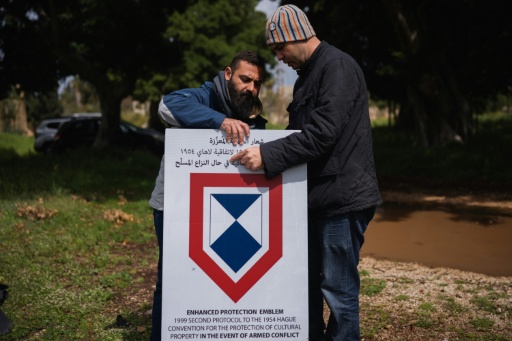 Des employés installent un panneau de l'Unesco sur le site de l'hippodrome romain de Tyr, dans le sud du Liban, le 23 mars 2026