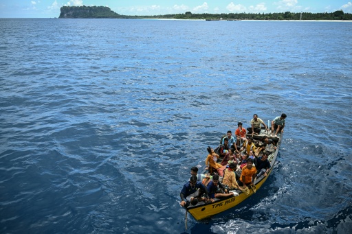 Des passagers sur un canot s'apprêtent à monter à bord du ferry Kalighat, l'unique lien entre Chowra et Car Nicobar, deux minuscules morceaux de l'archipel indien des Andaman-et-Nicobar, en plein cœur de l'océan Indien, le 30 mars 2026