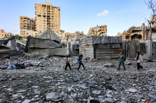 Des habitants passent devant un immeuble residentiel touche par une frappe israelienne dans le quartier d'Al-Ramal a Gaza