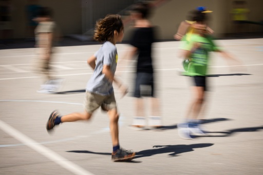 Des enfants courent dans une cour d'école, silhouettes floues en mouvement
