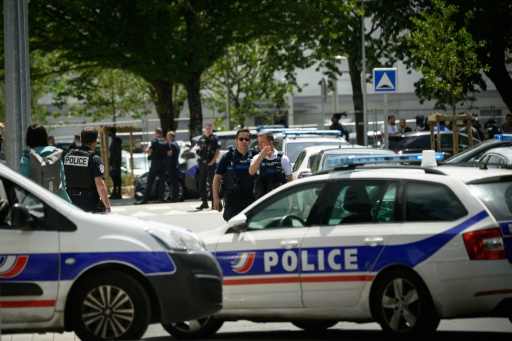 Des voitures de police et des policiers déployés sous les arbres, au pied d'immeubles