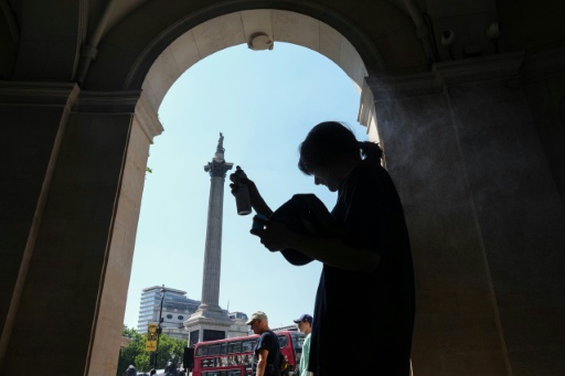 Une femme se protège du soleil à l'ombre d'une entrée sur Trafalgar Square, à Londres