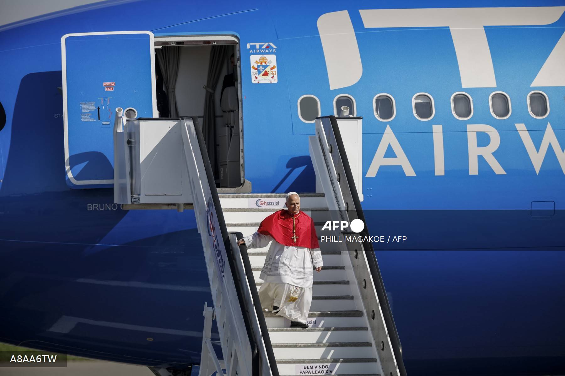Le pape Léon XIV descend l'escalier de l'avion ITA Airways à son arrivée à Luanda, devant le bandeau d'accueil Bem Vindo Papa Leão XIV, le 18 avril 2026