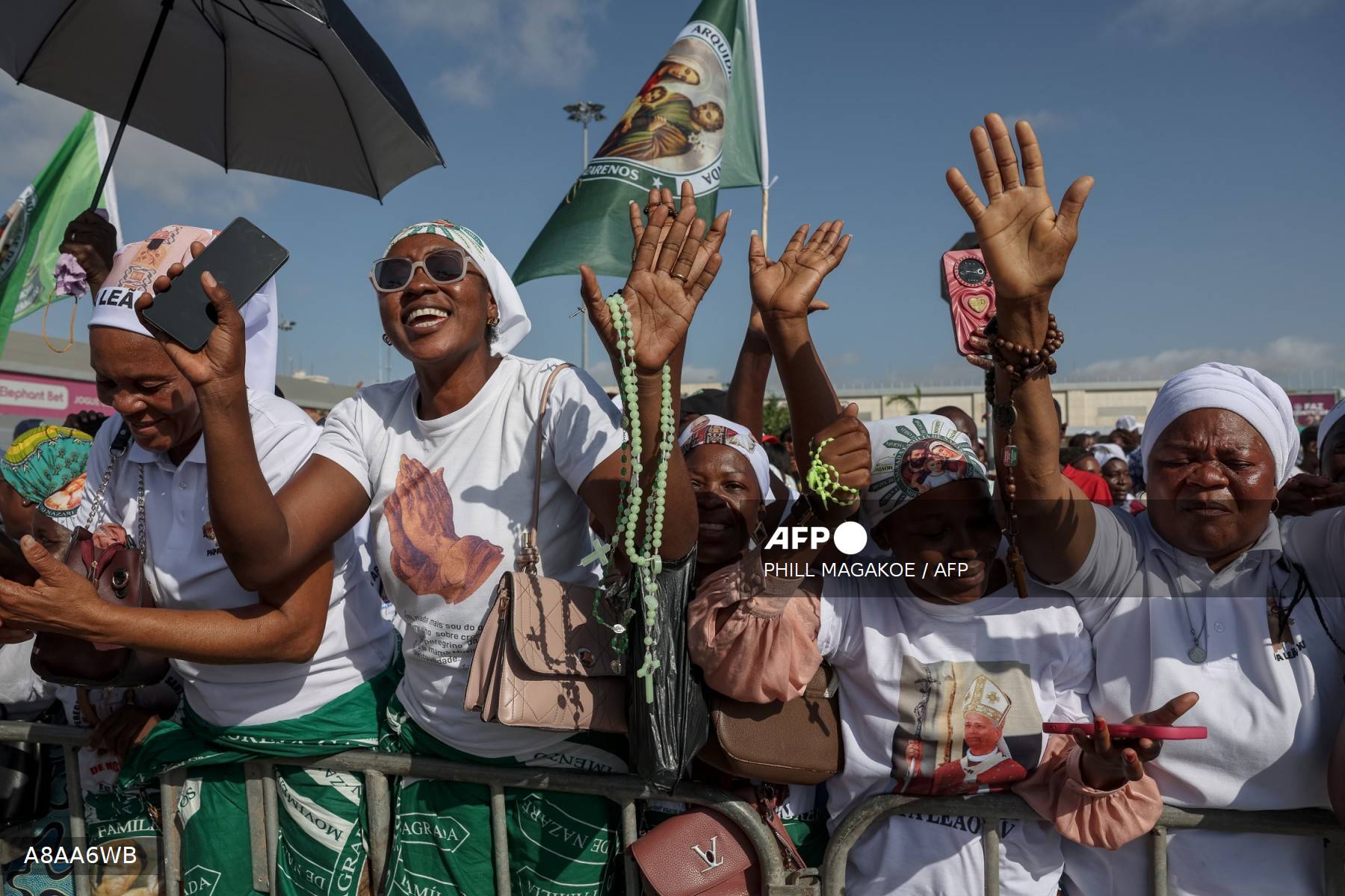 Des fidèles angolaises en tenues blanches et vertes lèvent les mains et agitent des chapelets pour accueillir le pape Léon XIV à son arrivée à Luanda le 18 avril 2026