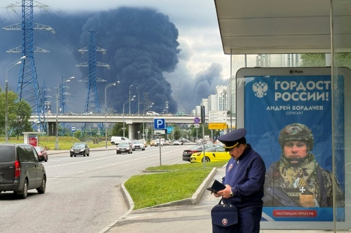 Un panneau de recrutement de l’armée russe devant les fumées de la raffinerie Gazpromneft touchée à Moscou