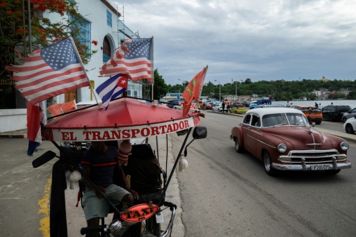 Un tricycle-taxi orné de drapeaux américains et cubain dans une rue de La Havane