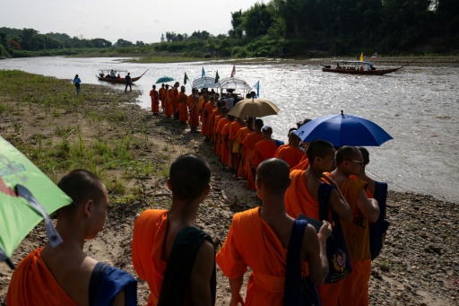 Des moines bouddhistes en robe safran marchent le long de la rivière Kok