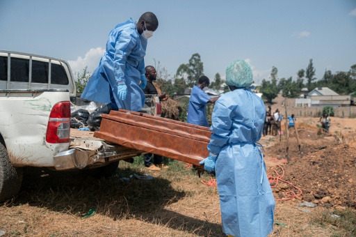 Un prêtre bénit une tombe lors de funérailles au cimetière de Mbiyo