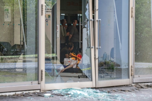 Des évacués se reposent parmi des éclats de verre à l'hôtel de ville d'Uki