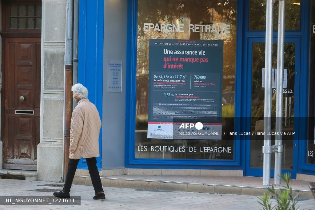 Une passante devant une vitrine de produits d'épargne, enseigne Les boutiques de l'épargne